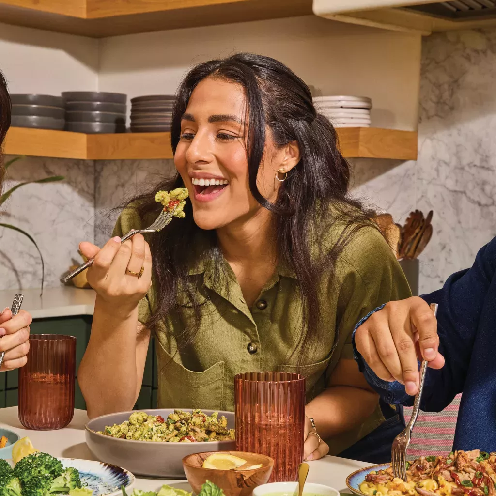 Customer enjoying Basil Pesto Cavatappi at a table with other customers.
