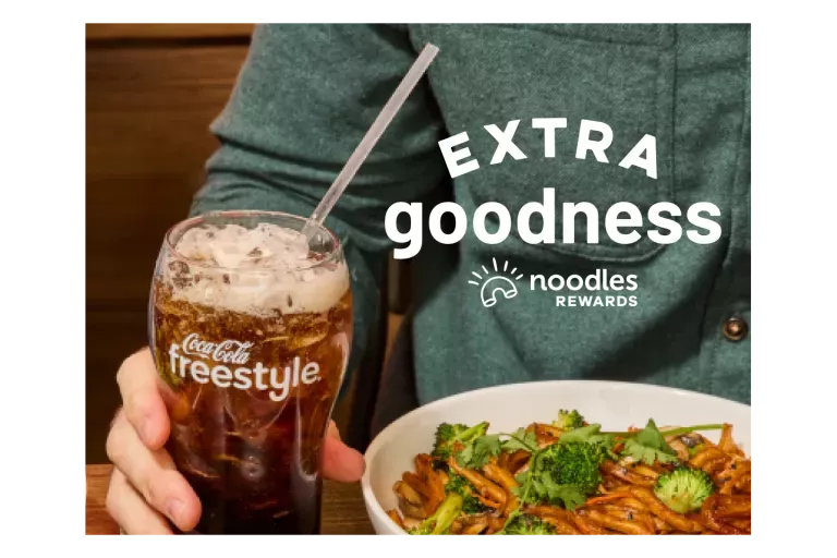Extra Goodness. Noodles Rewards Logo. Coca-Cola Freestyle Fountain Drink. Bowl of Japanese Pan Noodles on a table with a customer.