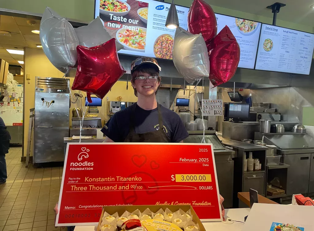 Noodles and Company 2025 Scholarship Award Winner holding a large check.
