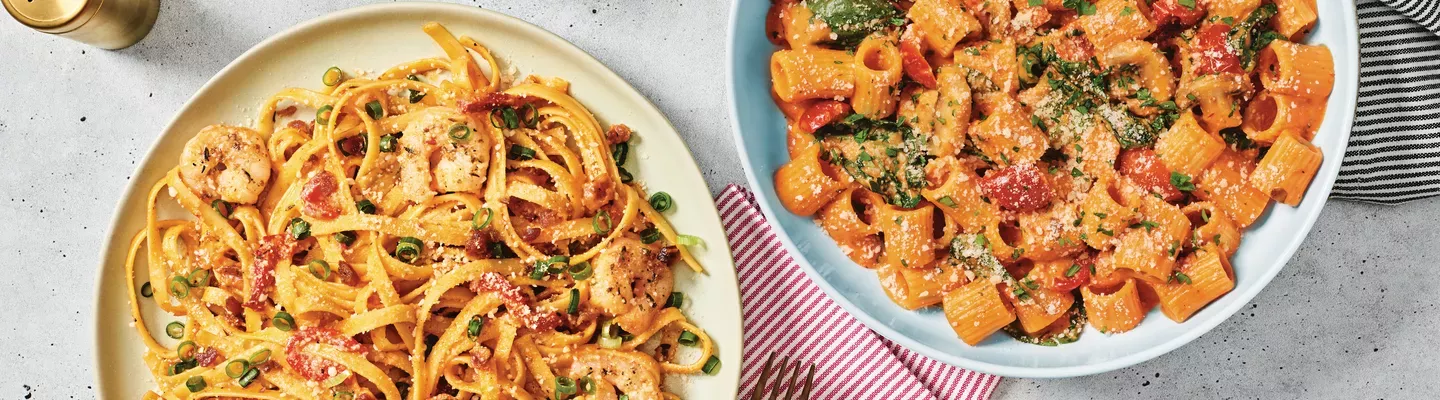 Entrees of Lemon Garlic Shrimp Scampi and Rigatoni Rosa on tabletop.